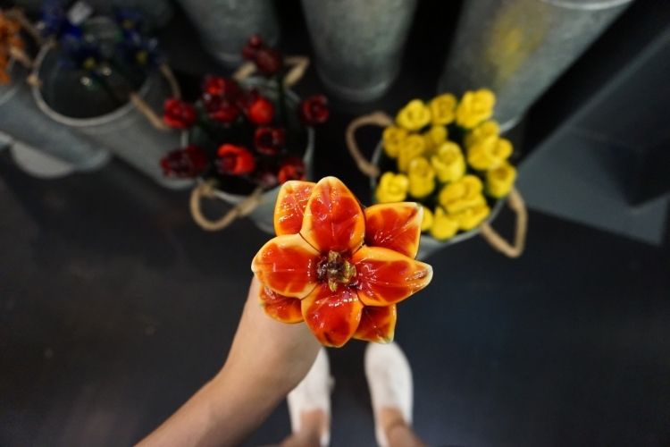 hand holding orange & yellow glass flowers